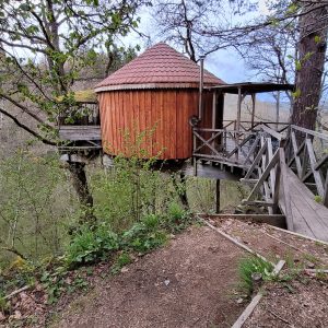 Cabane perchée en bois dans les arbres, entourée de verdure au Limousin.