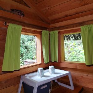 Cabane en bois dans le Languedoc-Roussillon, avec fenêtres et rideaux verts.