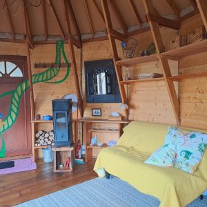 Hébergement insolite en Limousin : intérieur chaleureux avec un poêle et des murs en bois.