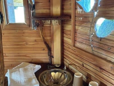 Hébergement insolite en bois avec lavabo en métal et décor naturel chaleureux.