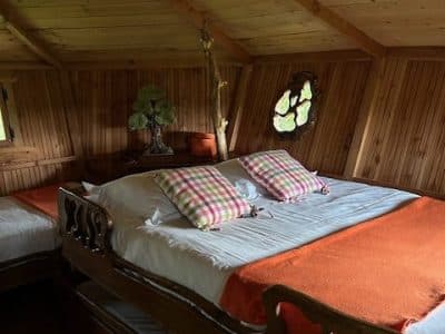 Chalet en bois avec lits douillets et coussins à carreaux colorés. Ambiance chaleureuse.