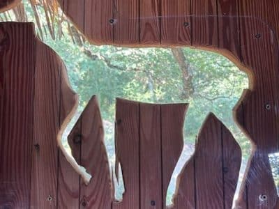 Hébergement insolite en bois avec une silhouette de cerf découpée dans le mur.