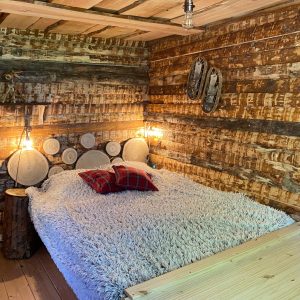 Chalet en bois chaleureux avec lit douillet et décor rustique en Auvergne-Rhône-Alpes.