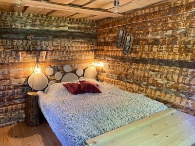 Chalet en bois chaleureux avec lit douillet et décor rustique en Auvergne-Rhône-Alpes.