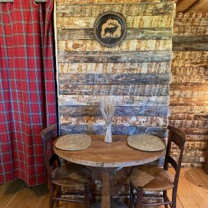 Cabane en bois avec table ronde et décor rustique, ambiance chaleureuse et authentique.