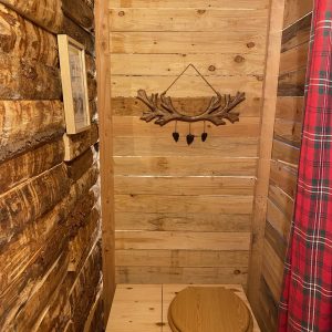 Cabane en bois avec toilettes en bois, décor rustique et ambiance chaleureuse.