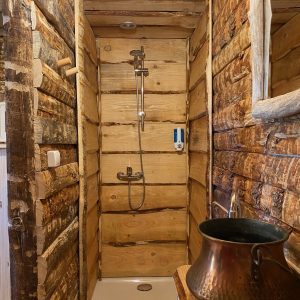 Douche en bois dans un hébergement insolite en Auvergne-Rhône-Alpes. Ambiance chaleureuse.