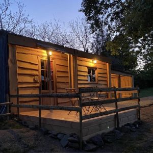 Cabane en bois éclairée, offrant une terrasse accueillante au cœur de lAuvergne.