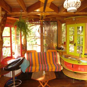 Cabane perchée à Limousin, intérieur coloré avec un canapé rayé et des plantes.
