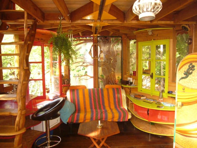 Cabane colorée dans les arbres avec un intérieur chaleureux et lumineux.