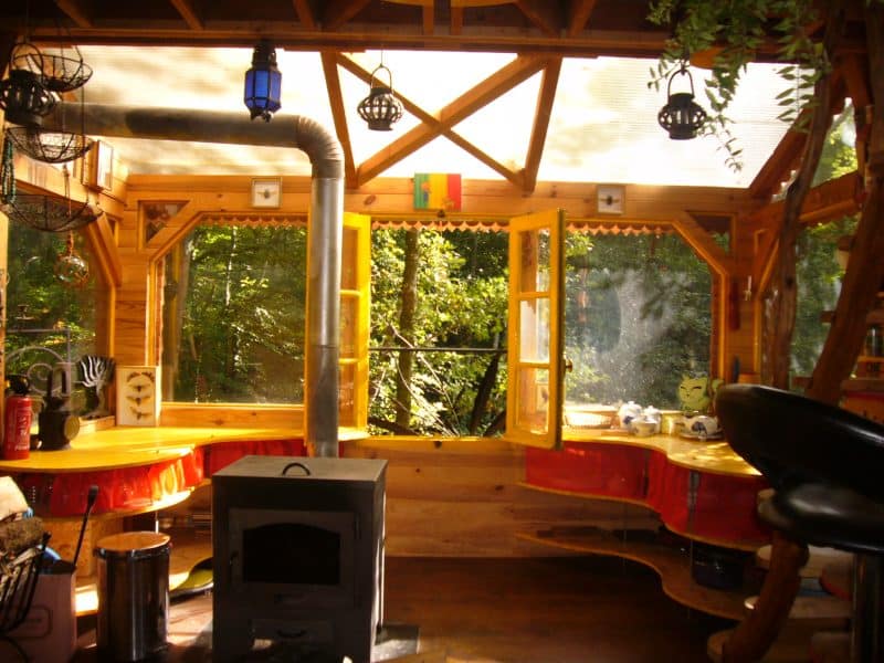 Cabane en bois avec grandes fenêtres, offrant une vue sur la nature environnante.