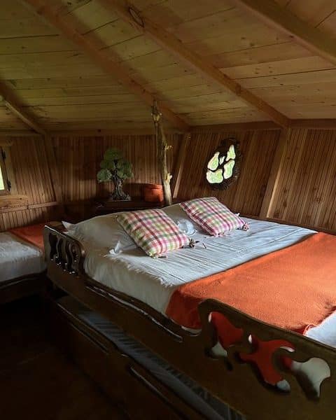 Chalet en bois chaleureux avec lit douillet et coussins colorés.