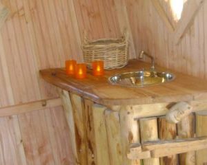 Hébergement insolite en bois avec un lavabo en bois et des bougies décoratives.