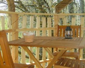 Cabane dans les arbres avec terrasse en bois et lanternes, idéale pour un séjour unique.