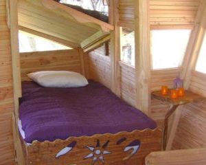Cabane perchée avec lit douillet et vue sur la nature environnante.