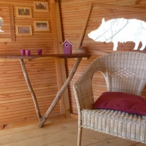 Hébergement insolite en bois avec une chaise en osier et des décorations originales.