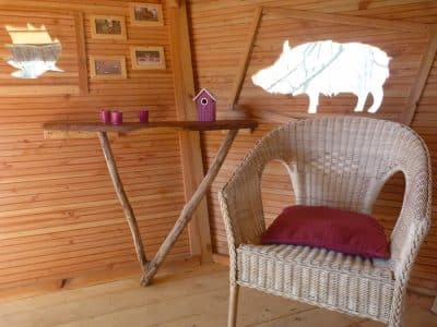 Hébergement insolite en bois avec une chaise en osier et des décorations originales.