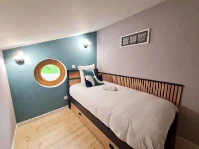 Chambre atypique en Bourgogne-Franche-Comté avec fenêtre ronde et décor moderne.
