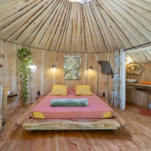 Yourte en bois avec lit douillet, décor naturel et ambiance chaleureuse.