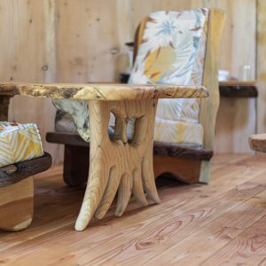 Hébergement insolite en bois, avec des meubles sculptés et des coussins colorés.