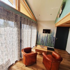 Hébergement insolite en Bourgogne-Franche-Comté avec salon lumineux et fauteuils en cuir.