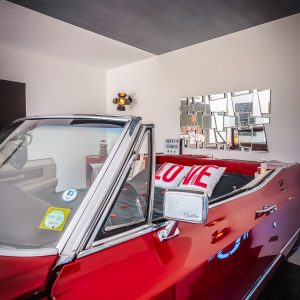 Hébergement insolite : voiture vintage rouge transformée en chambre à coucher moderne.