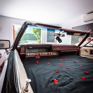 Hébergement insolite : voiture vintage transformée en chambre, décorée de pétales de rose.