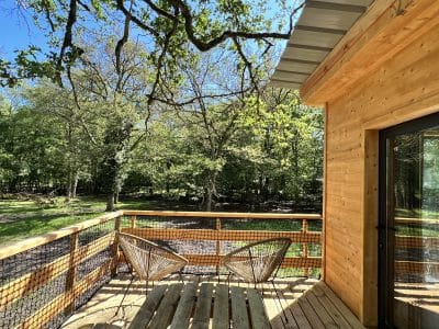 Cabane en bois avec terrasse, entourée de verdure en Auvergne-Rhône-Alpes.