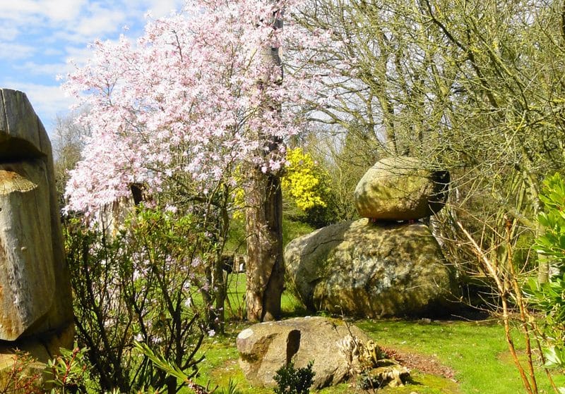 Hébergement en pleine nature avec sculptures en bois et arbres fleuris.