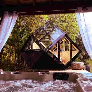 Hébergement insolite en forme de cube avec jacuzzi, entouré de verdure apaisante.