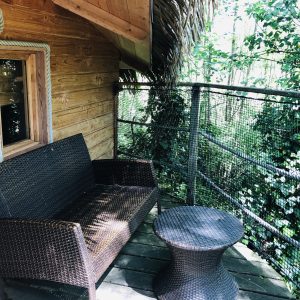 Cabane perchée en Auvergne-Rhône-Alpes avec terrasse en bois et mobilier en rotin.