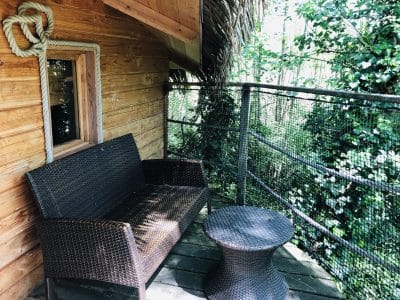 Cabane perchée en Auvergne-Rhône-Alpes avec terrasse en bois et mobilier en rotin.