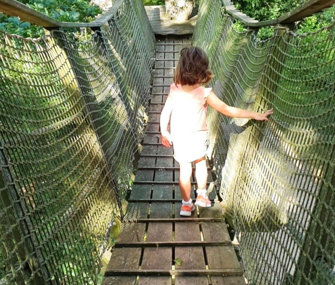 Enfant traversant un pont suspendu vers un hébergement insolite en Auvergne-Rhône-Alpes.