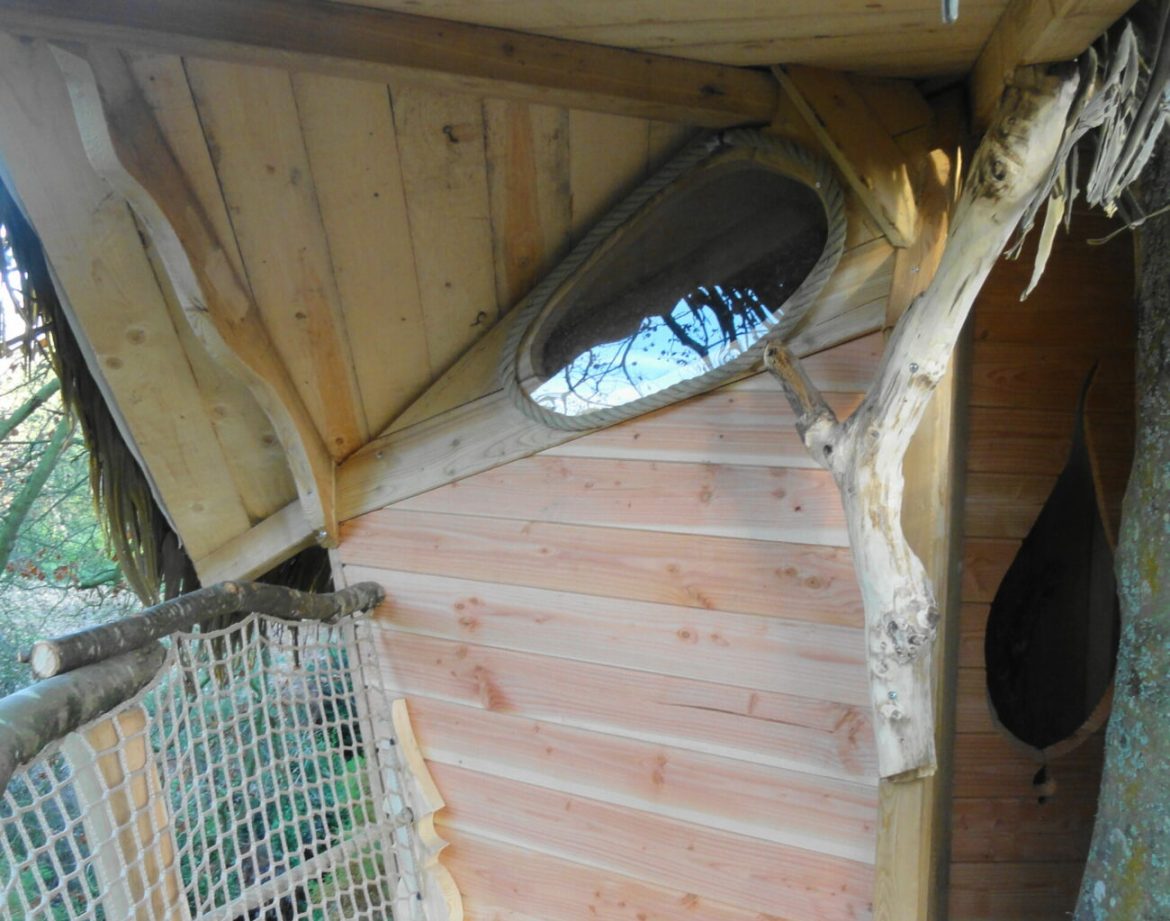 Cabane perchée en Bretagne, avec un miroir rond et des finitions en bois naturel.
