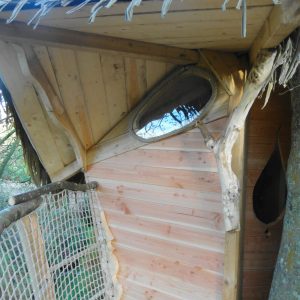 Cabane perchée en Bretagne, avec un miroir rond et des finitions en bois naturel.