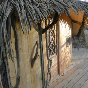 Cabane en bois avec toit de chaume, située en Bretagne, au milieu de la nature.