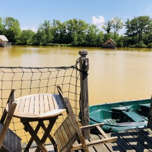 Cabane flottante en Auvergne-Rhône-Alpes, vue sur un lac paisible et verdoyant.