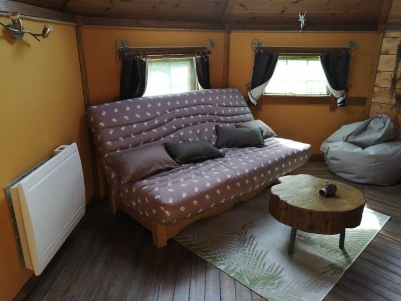 Chalet cosy avec un canapé confortable et des fenêtres lumineuses.