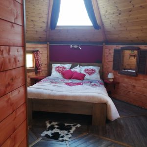 Cabane romantique en bois avec lit douillet et décor chaleureux à Midi-Pyrénées.
