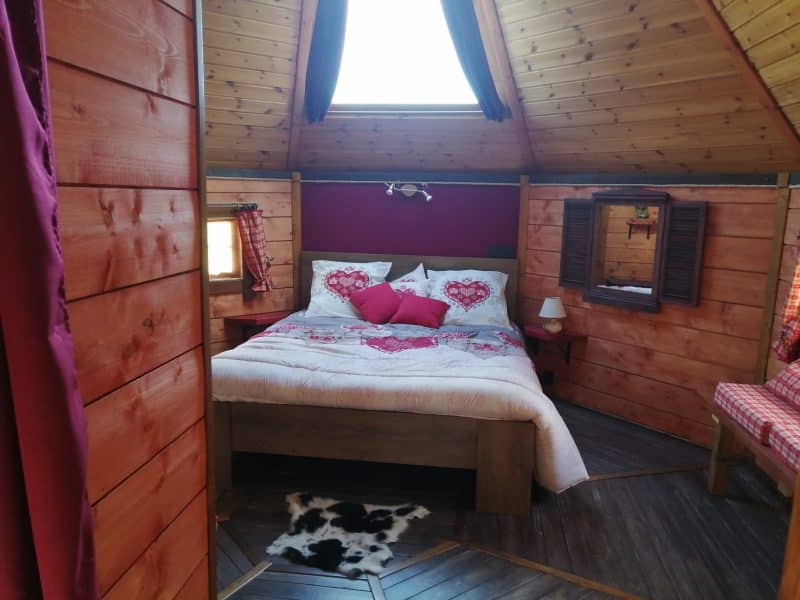 Chalet romantique avec lit douillet et décor en bois chaleureux.