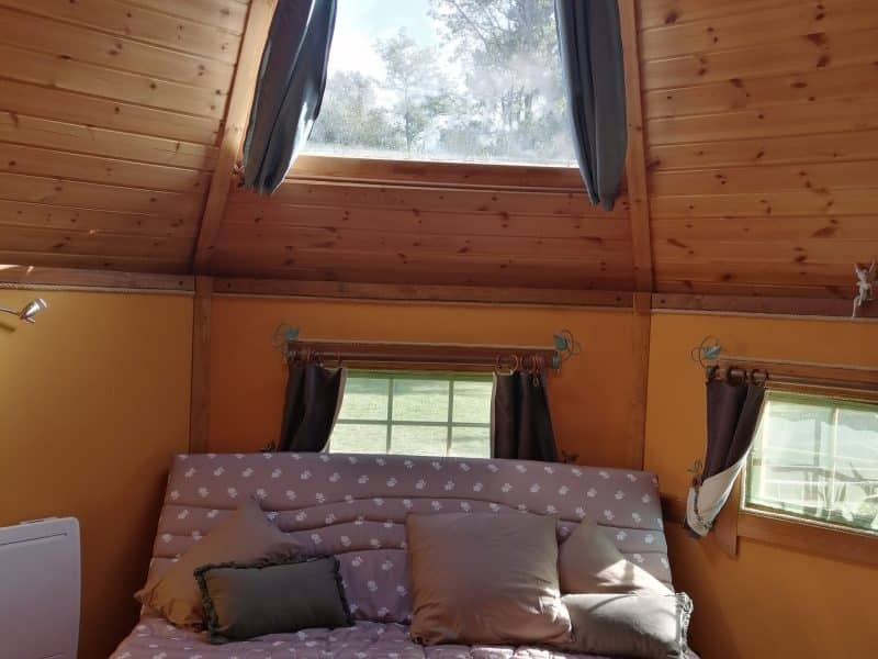 Cabane en bois avec un canapé confortable et un puits de lumière.
