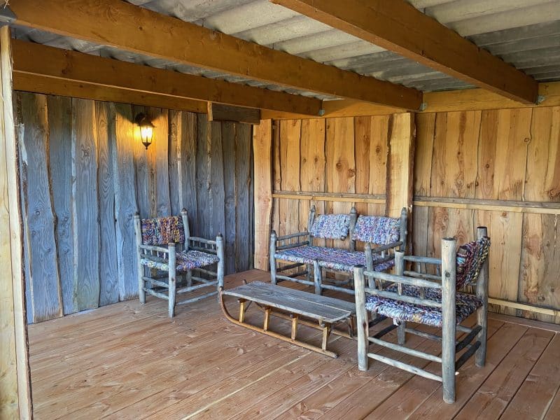Cabane en bois avec des fauteuils colorés et une table en bois sur un plancher en bois.