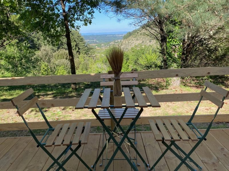 Chalet en bois avec vue panoramique, table et chaises en bois sur la terrasse.