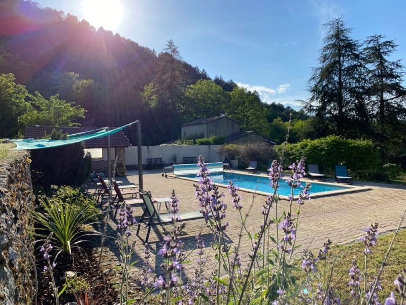 Charmante villa avec piscine, entourée de verdure et de fleurs colorées.