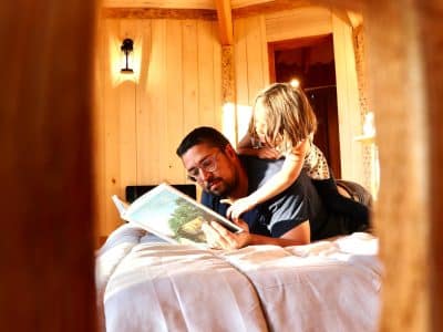 Hébergement insolite en bois en Auvergne-Rhône-Alpes, père et fille lisent ensemble.