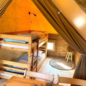 Tente lodge en bois avec lits superposés et décoration chaleureuse en Auvergne-Rhône-Alpes.