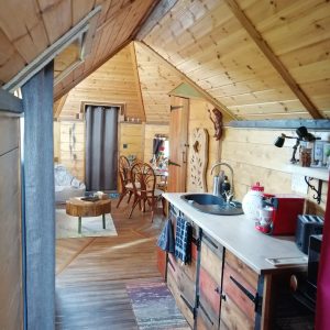 Cabane en bois cosy avec intérieur chaleureux et cuisine équipée.