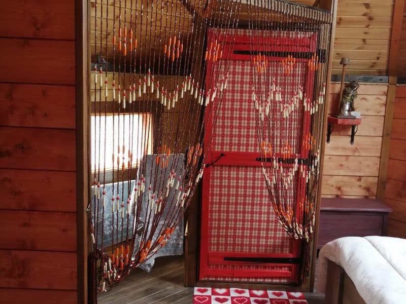 Chalet en bois avec rideaux en perles et tapis à motifs coeurs. Ambiance chaleureuse.