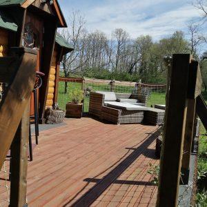Cabane en bois avec terrasse ensoleillée et mobilier de jardin confortable.