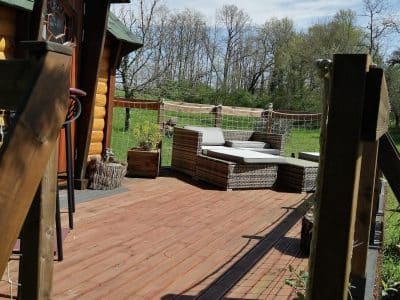 Cabane en bois avec terrasse ensoleillée et mobilier de jardin confortable.